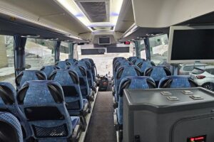 The image shows the interior of a modern, empty bus with blue patterned seats, seatbelts, and large windows revealing snowy scenery—ideal transport for visitors heading to a Tour from Tallinn to East Estonia